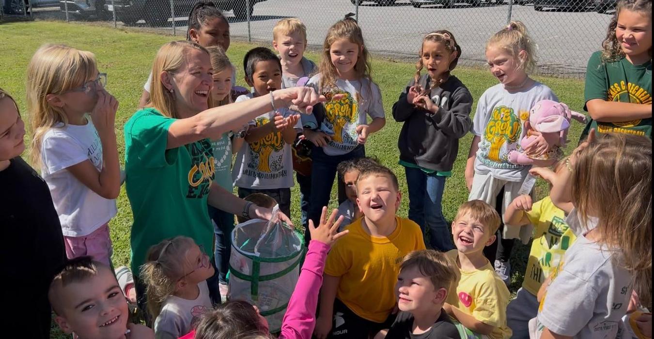 A group of children and an adult engaging joyfully during an outdoor activity.