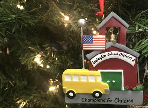 Ornament on a Christmas tree with a school bus and school house