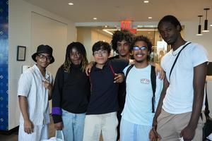 Group of six young men posing together in a modern setting.