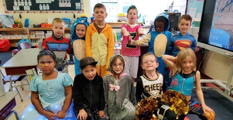 Children in costumes for a themed event gather for a photo.