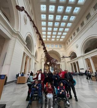 Group of people posing in a museum under a dinosaur skeleton.