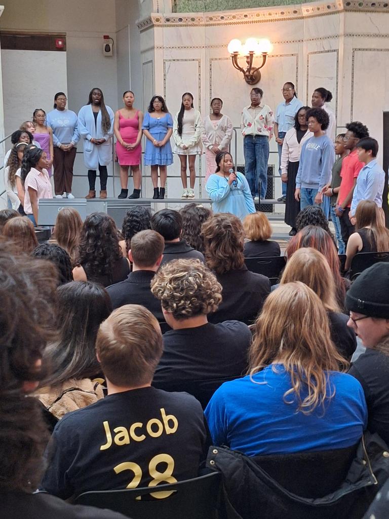 Choir singing in front of seated crowd.