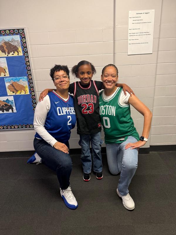 Image shows two adults and a scholar dressed in similar outfits with jeans and jerseys