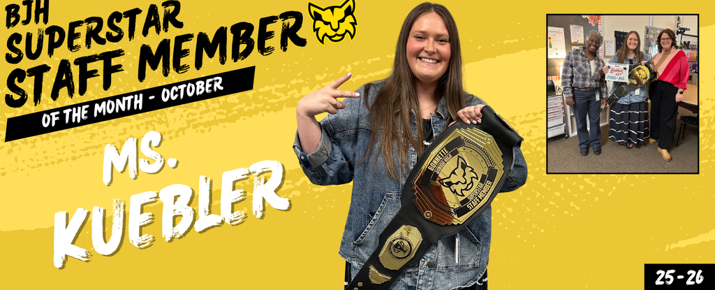 A smiling woman in a denim jacket holds a championship belt, posing with staff members.