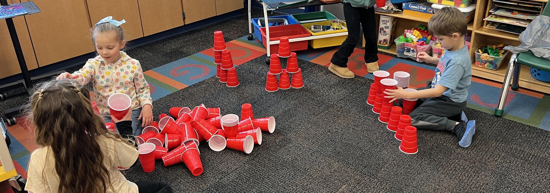 4 students in classroom stacking red cups