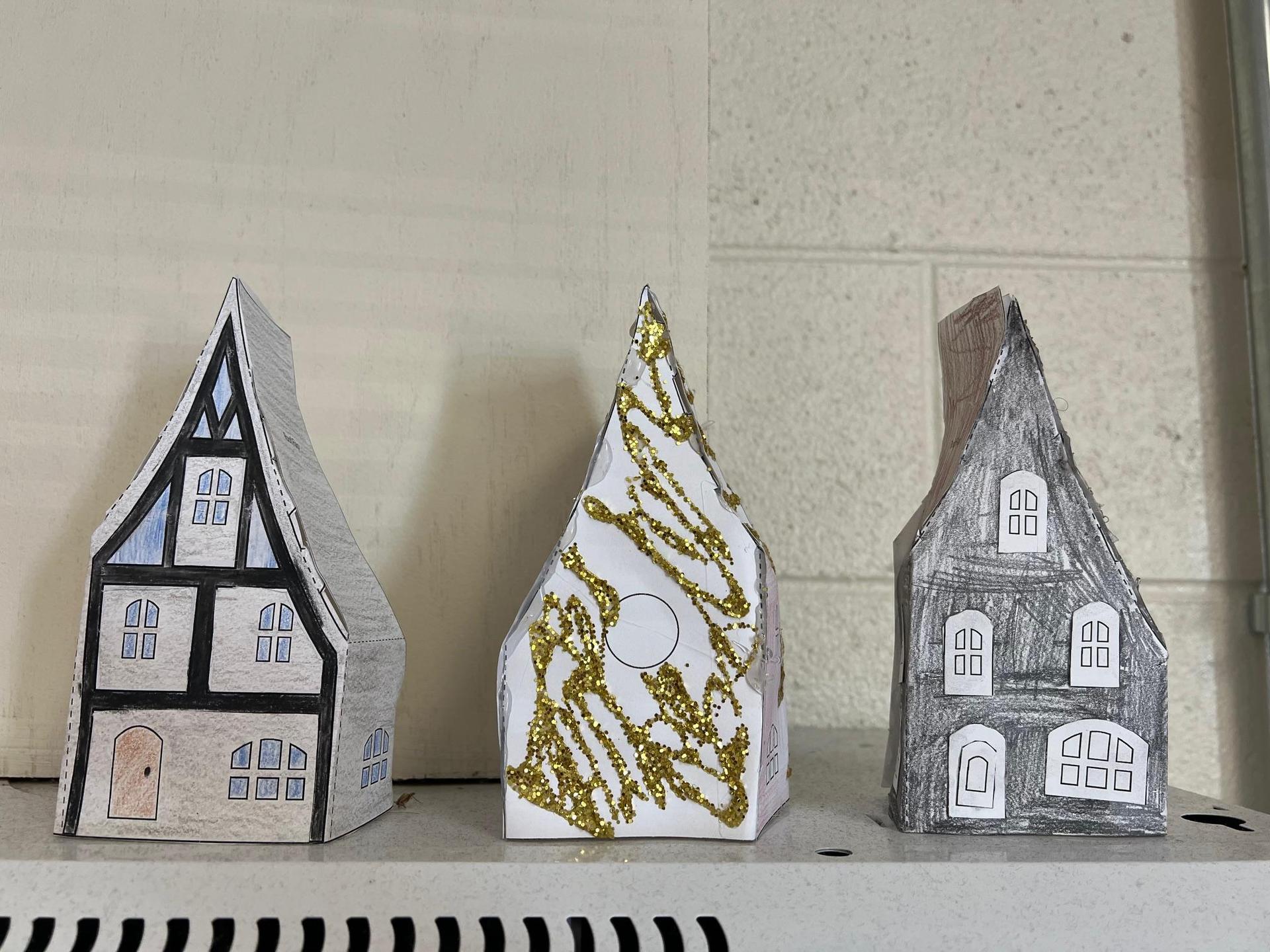 Three uniquely designed paper houses with various colors and embellishments.