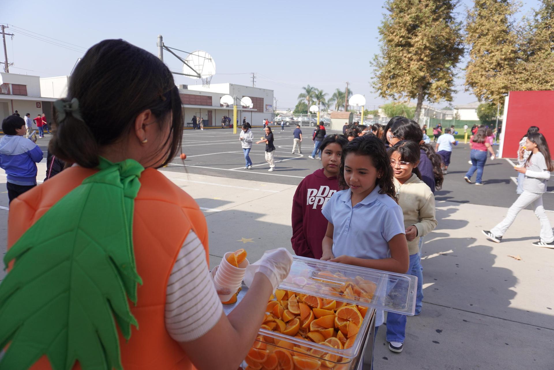 Students lining up to learn health facts about oranges