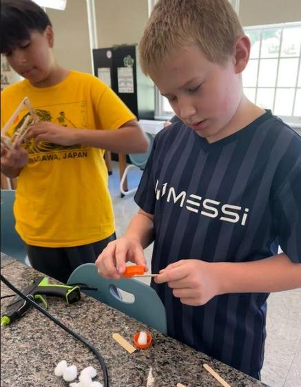 Two boys working on a science project, one assembling a model.