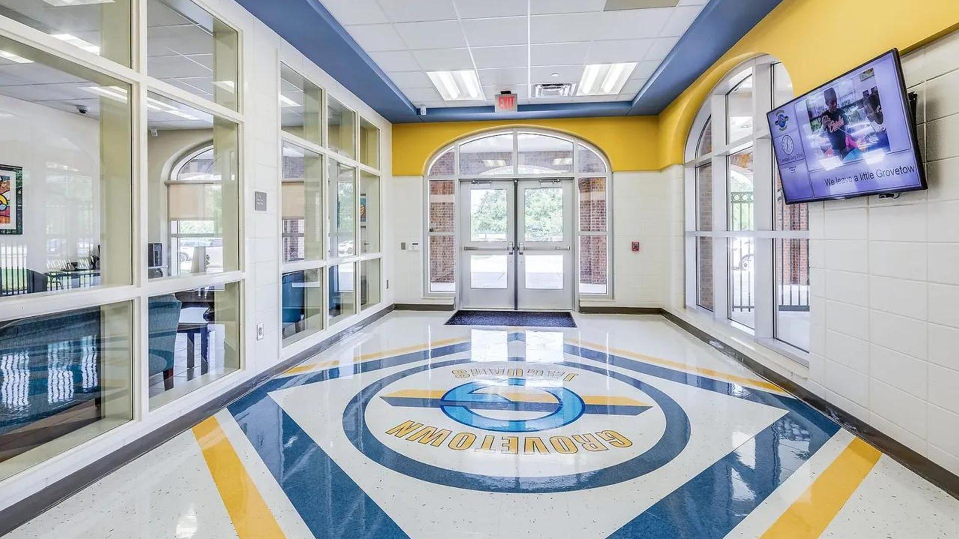 Bright hallway with large windows and a logo on the floor.