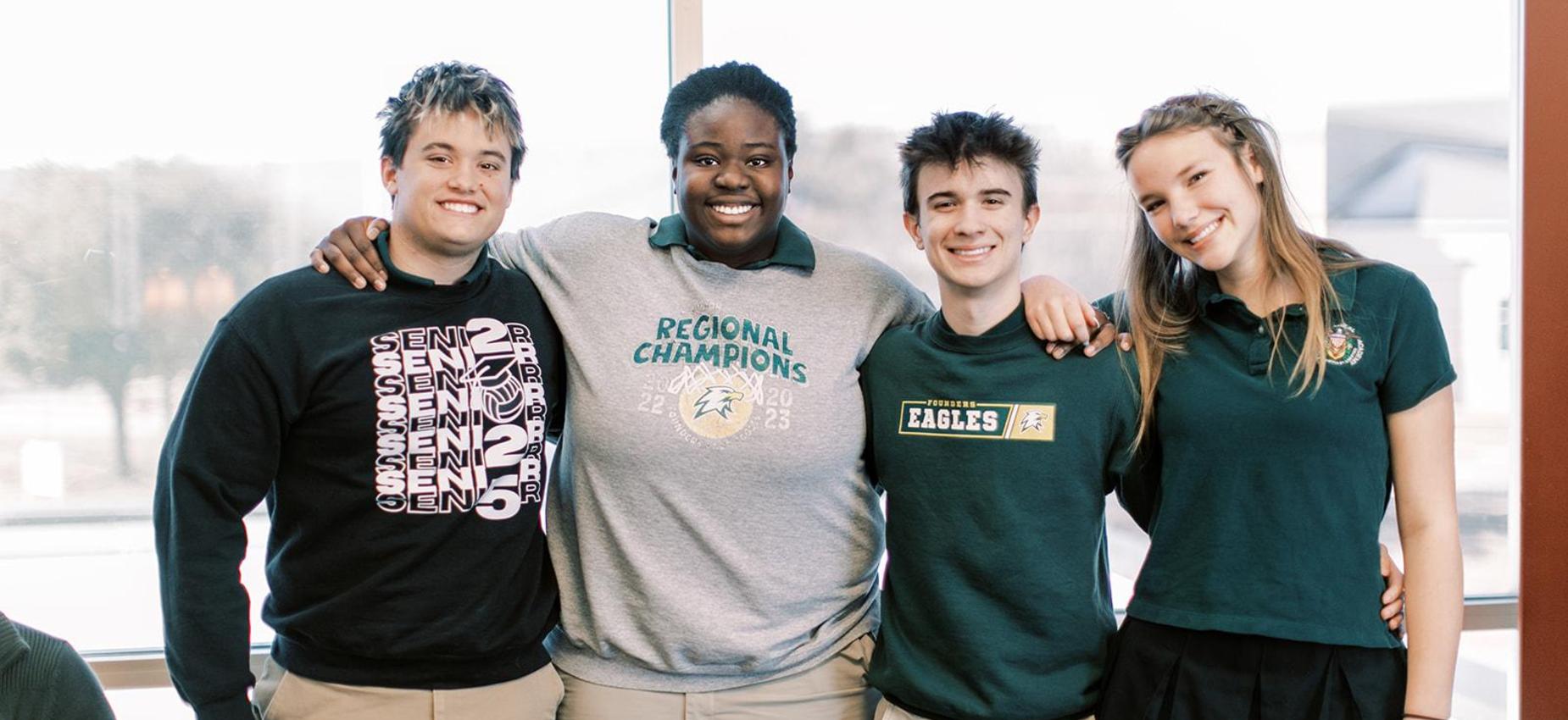 Four smiling high school students stand together outside