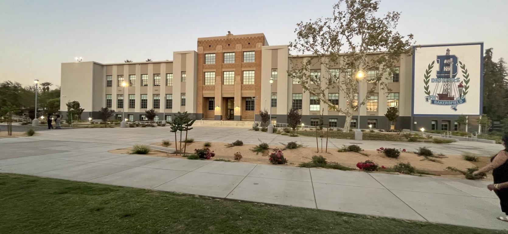 A historic school building with modern landscaping and evening lighting.