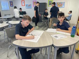 2 eighth grade boys sitting at desks and filling out worksheets