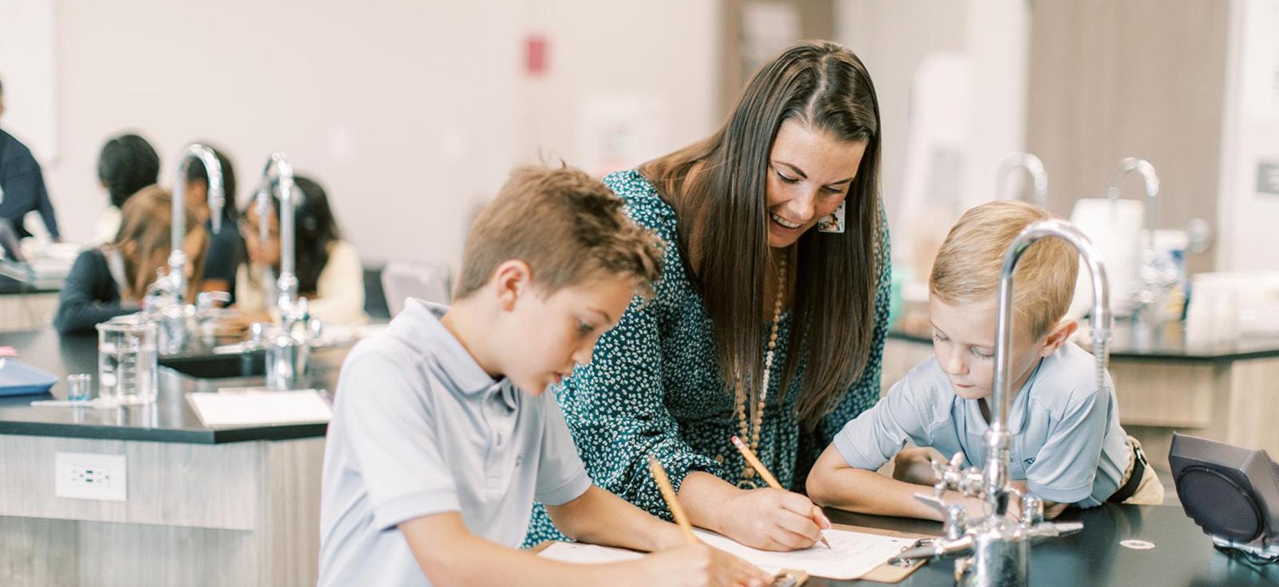 A teacher helps two students during a science lesson