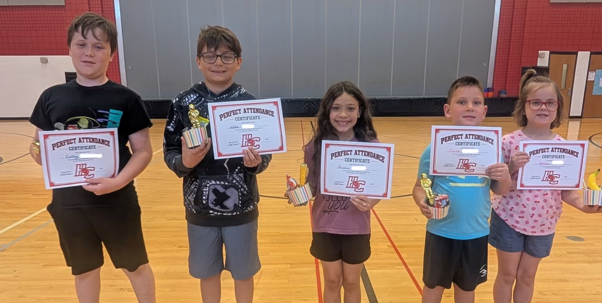 Five children holding certificates and trophies, celebrating their achievements.