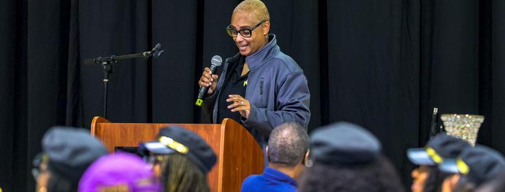 A speaker addressing an audience with a microphone at a podium.