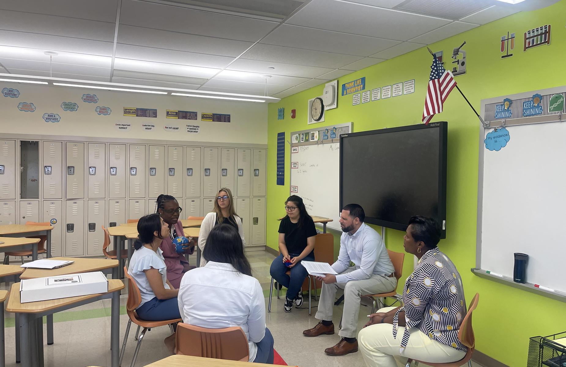 Group discussion among educators in a colorful classroom setting.