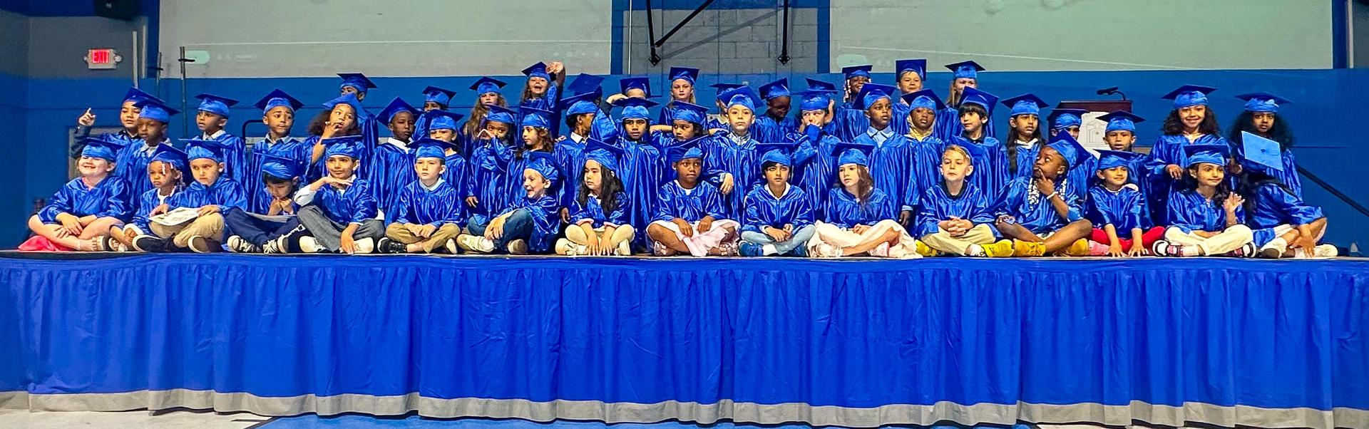 Seated kindergarten graduates in cap and gown
