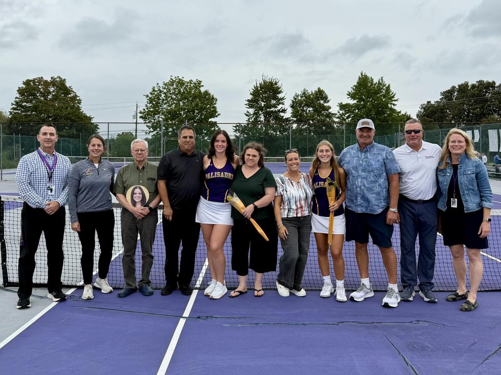 Senior tennis players and high school administrators in a group photo on the court.