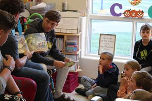 three football players read book while students look on