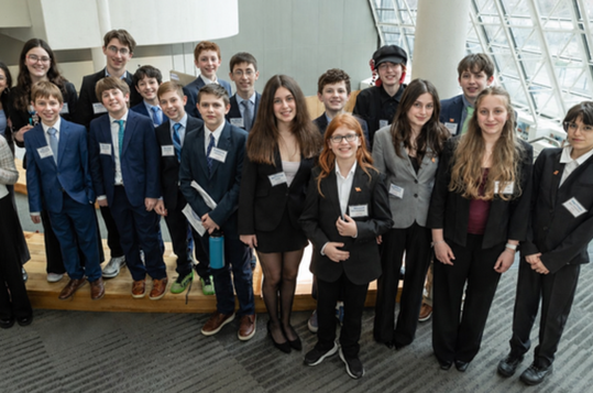 Group of young people dressed in formal attire, smiling at a public event.
