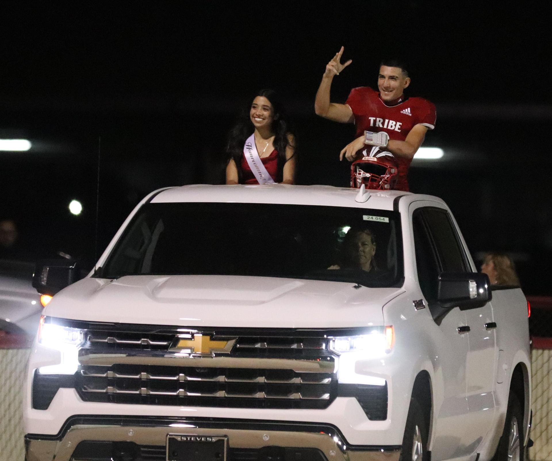 homecoming king and queen candidates entering the stadium in trucks
