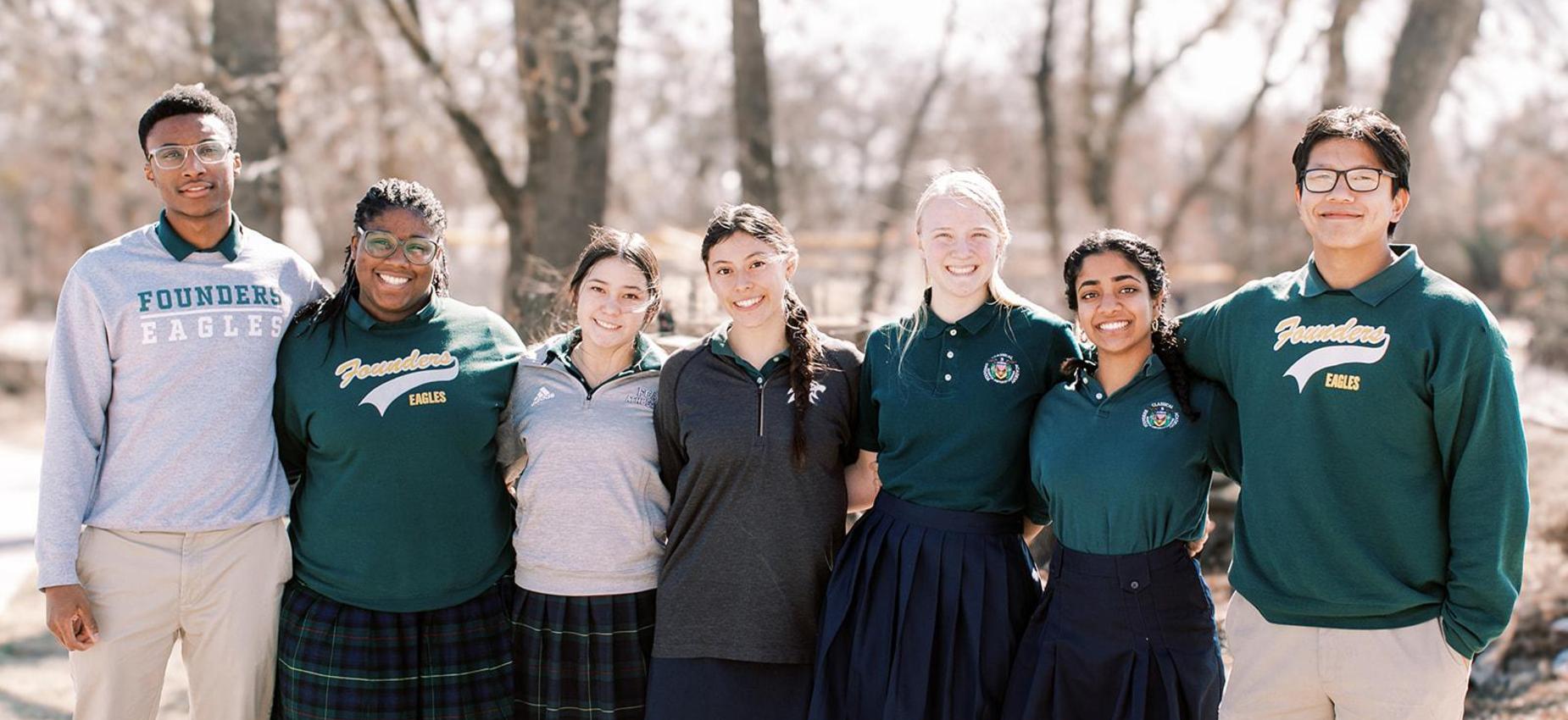 Group of smiling high school students in uniform stands together outside
