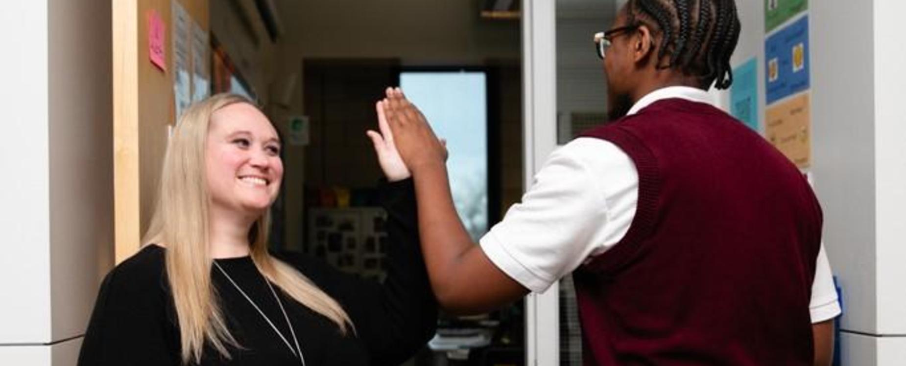 A woman and a person giving each other a high five indoors.