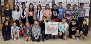 Students smiling in front of the '50 States Challenge' display holding a colorful map.