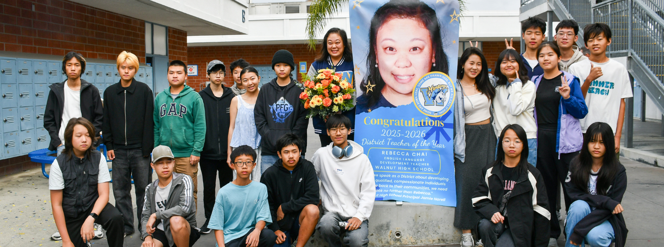 Students posing with their teacher's congratulations banner and flowers.