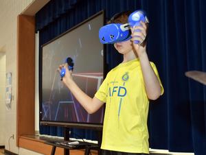a boy with a VR headset and paddles playing a video game.