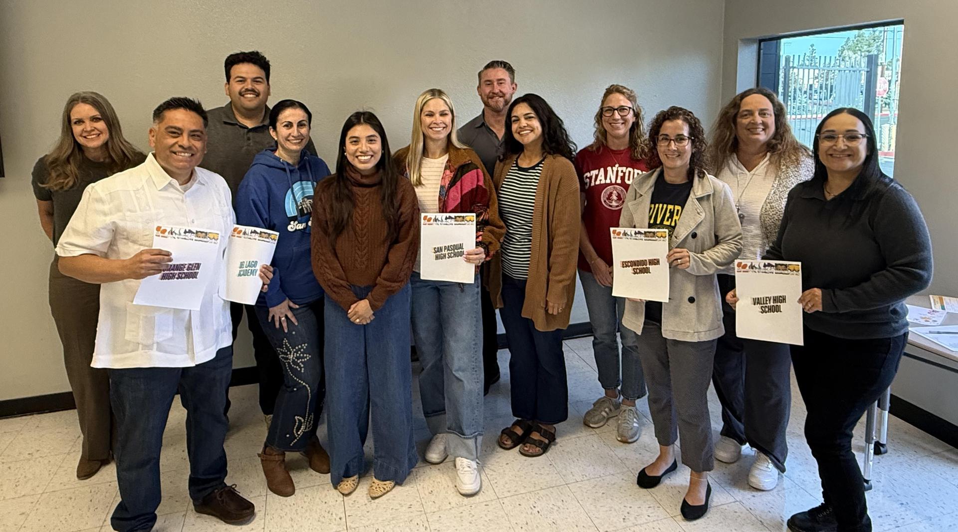 Group of school counselors smiling and holding school signs