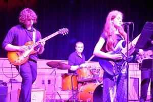 Band performing on stage with a singer and musicians.