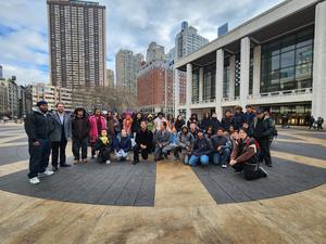 A large group of people gathered in front of a cultural building in a city square.