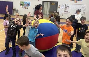 Students in gym wave at the camera.