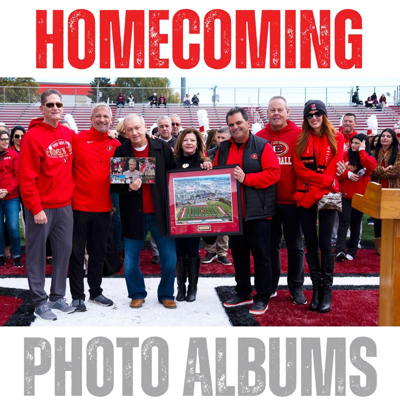 Group of people at a homecoming event holding memorabilia and posing for a photo.
