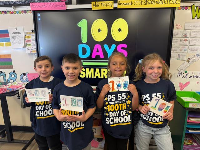 Four children holding artwork in front of a screen celebrating 100 days of school.
