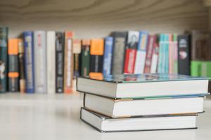 Three books near a bookshelf containing books