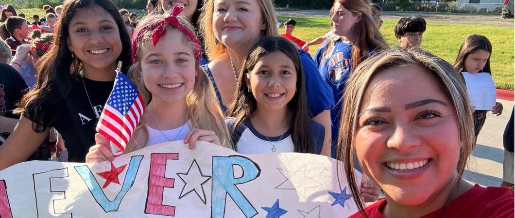 Children and staff smiling with a 9/11 remembrance poster.