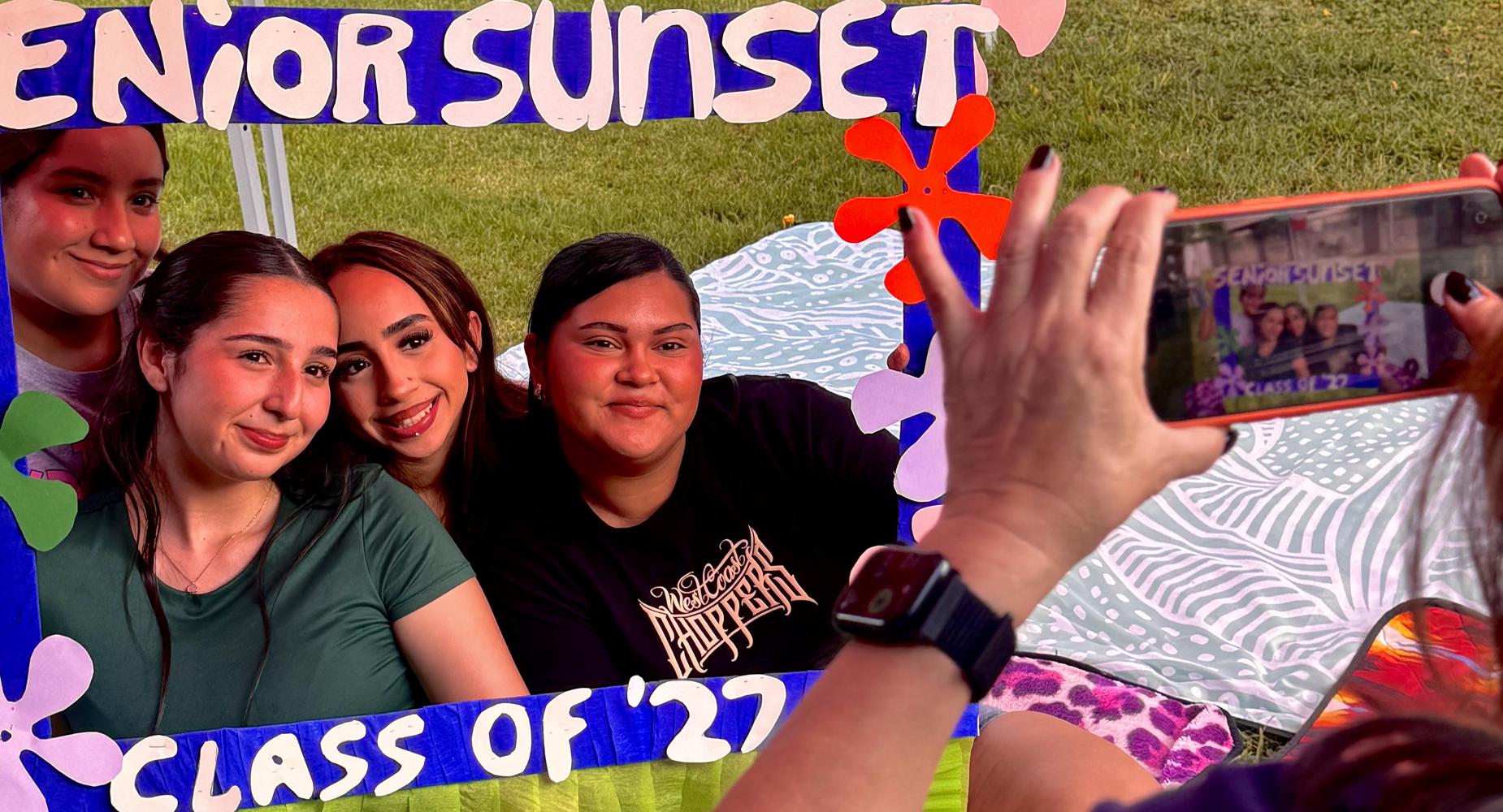 Senior sunset image of students taking a photo.