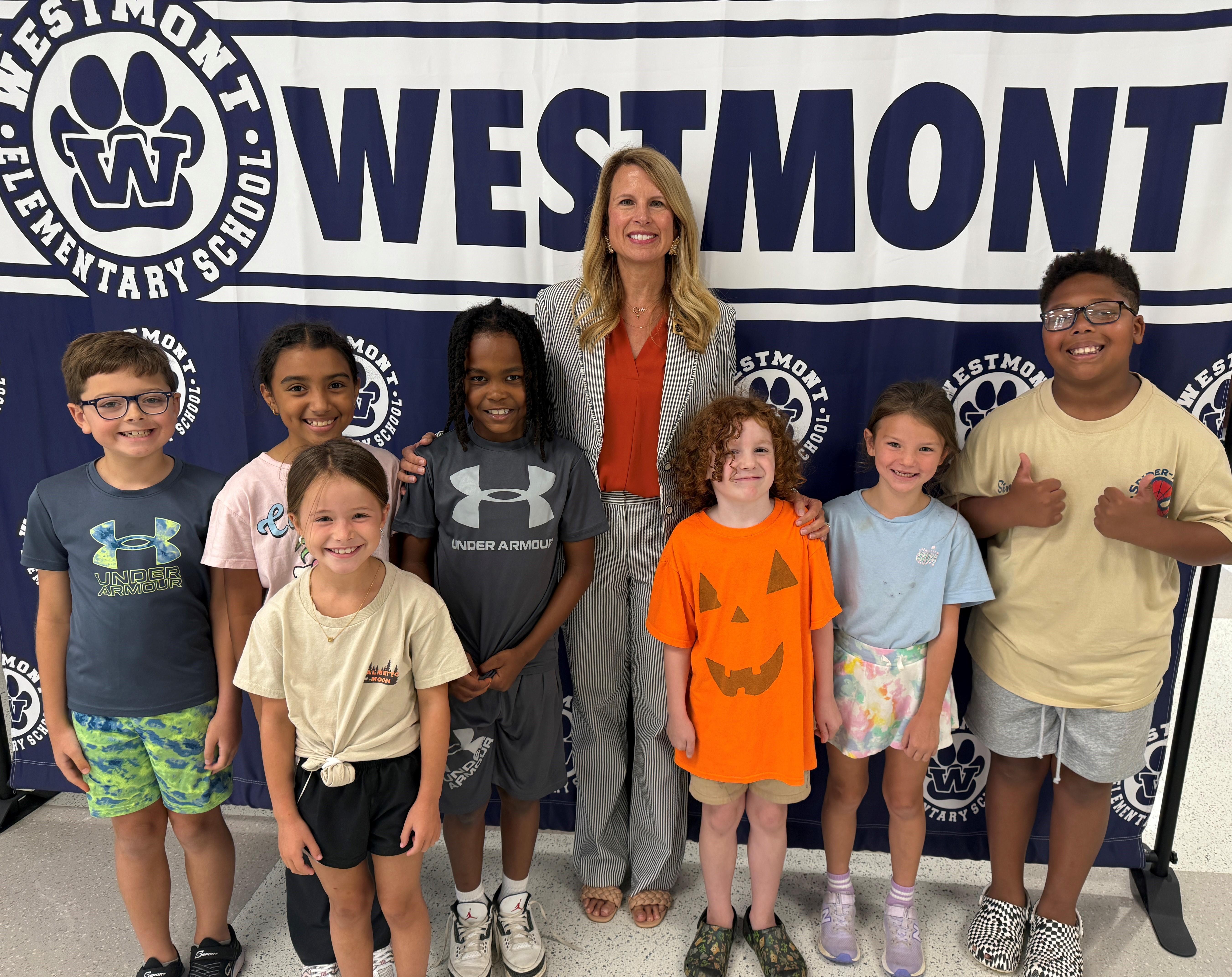 Principal standing with students in front of school backdrop