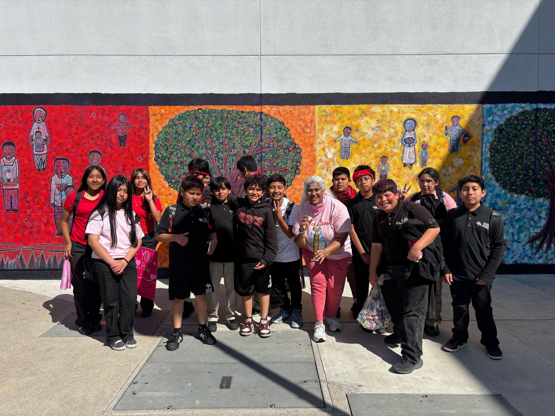 Students celebrate victory in front of school mural