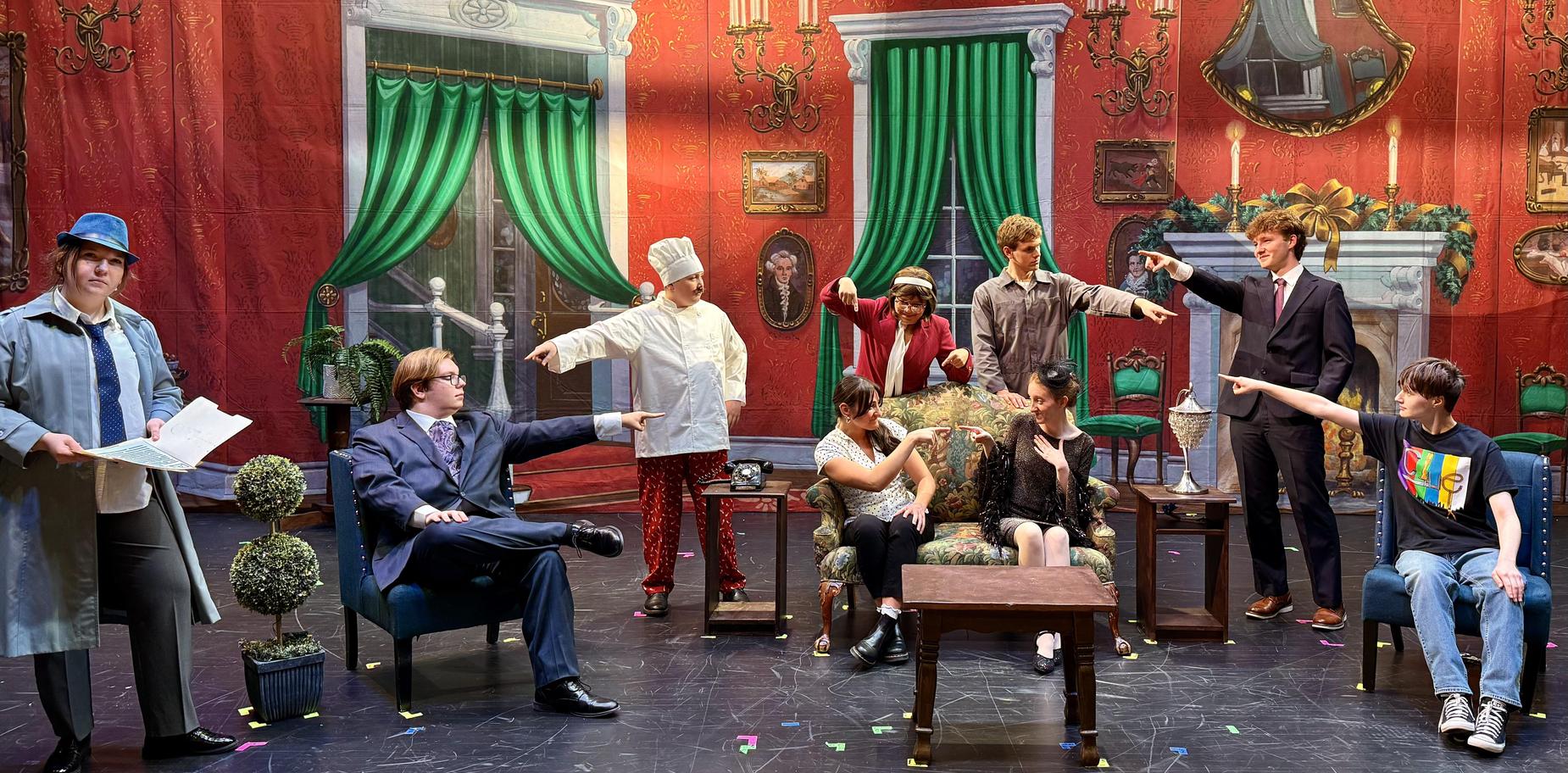Actors on stage in a themed set, portraying a scene with various characters and props.