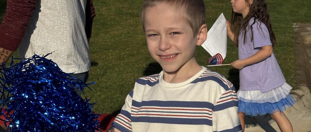 A child holding a blue pom pom.