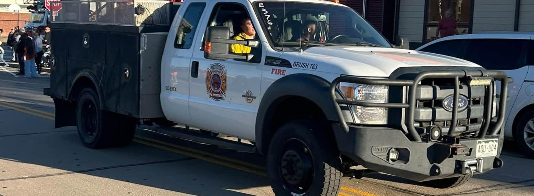 Fire truck with individuals inside, parked on a street during an event.