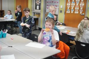 A student enjoys a donut treat on 100th day.
