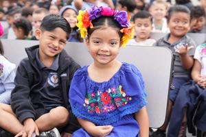Two students in cultural dress sitting on bench