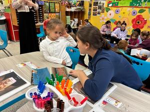 a seventh grade girl read her Gadol picture book to a kindergarten student.