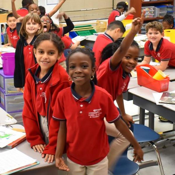 Children in red polo shirts posing excitedly for the camera.
