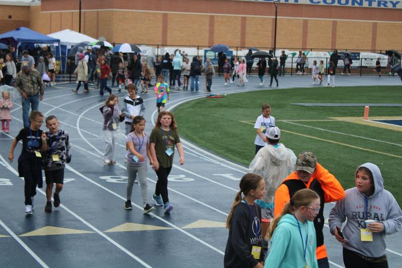 elementary students run around track while raining