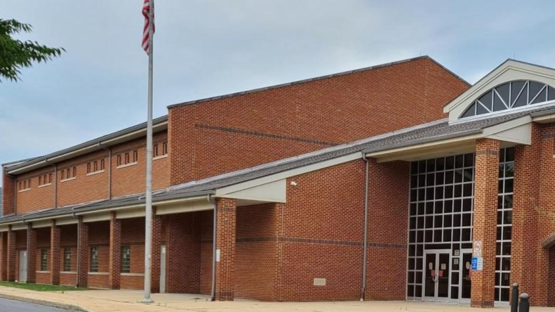 Red brick school building with tall windows and an American flag.
